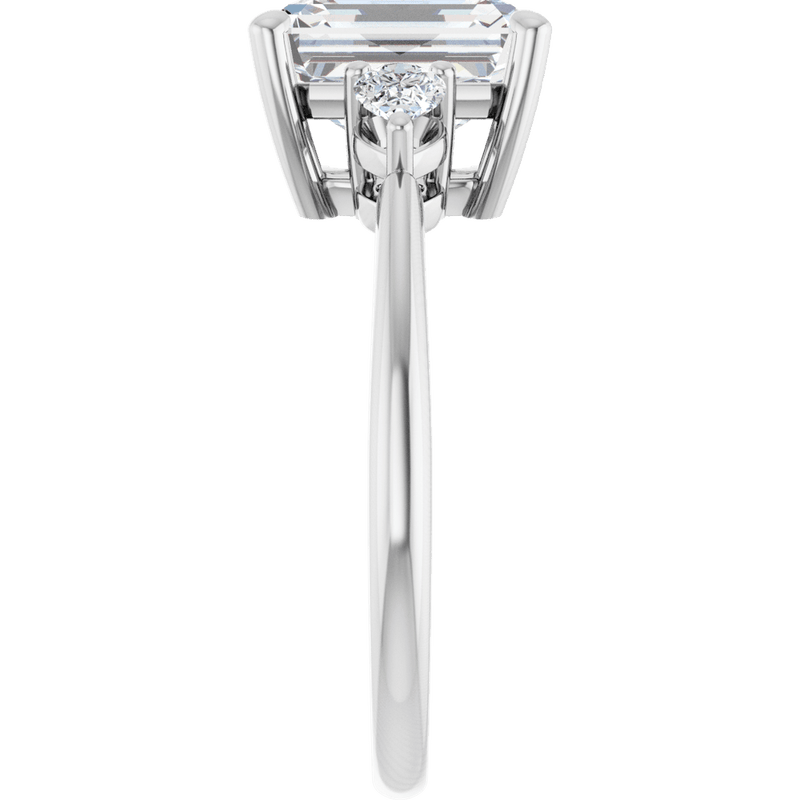 Side view of an emerald cut diamond engagement ring in white gold with a side accent diamond.
