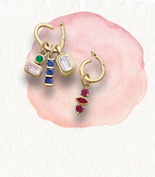 Gold hoop earrings with colorful gemstone charms including emerald, sapphire, and ruby.