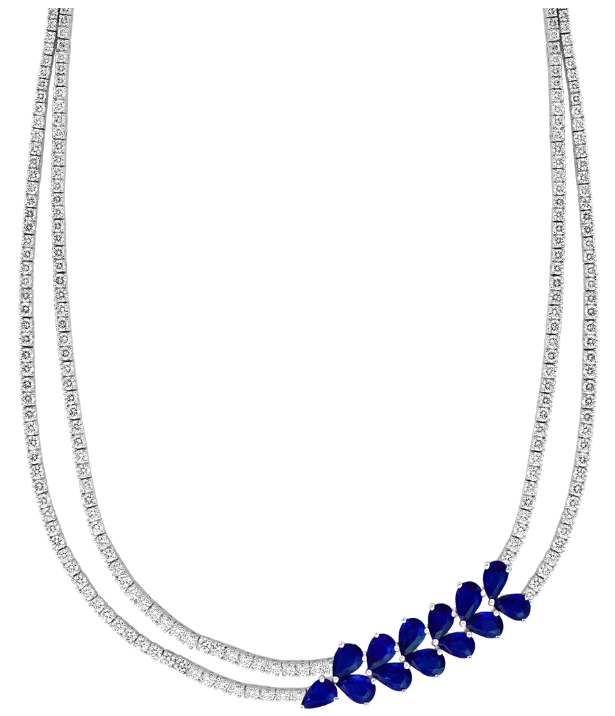 A delicate silver-toned necklace featuring a curved row of small, dark blue teardrop-shaped crystals at the center, displayed against a solid white background.