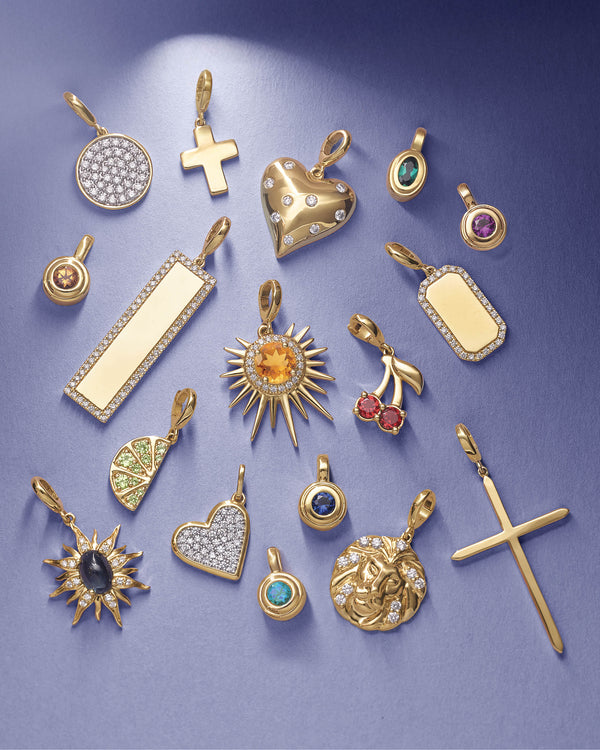 Assorted luxury gold pendants with diamonds, gemstones, and celestial designs on blue background.