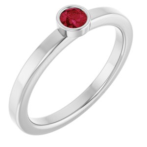 Solitaire silver ring featuring a round cut red gemstone in a bezel setting.