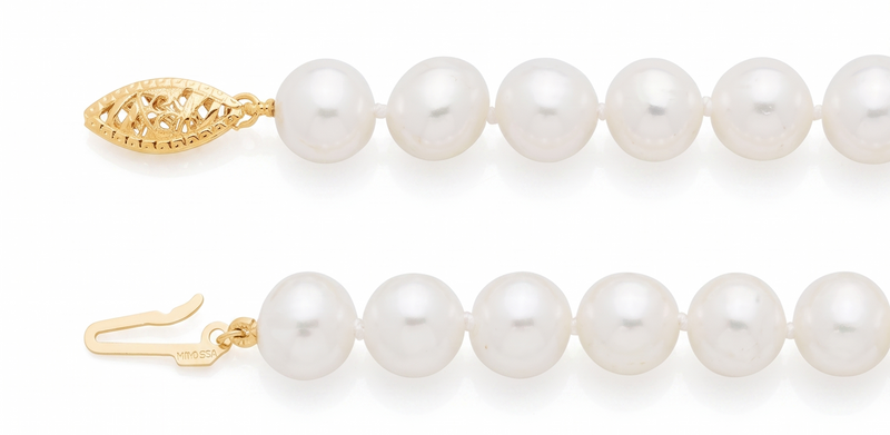 A close-up of a pearl strand necklace with white round pearls and gold-toned hardware, including a decorative clasp and hook, shown on a white background.