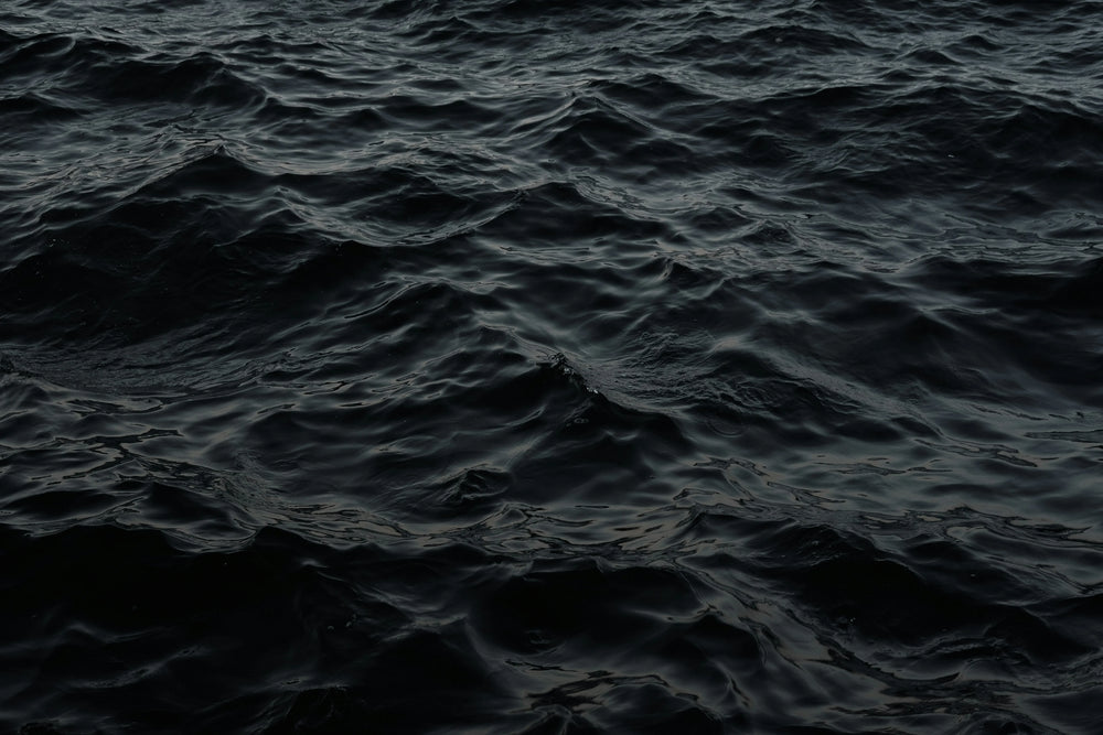 Dark, undulating ocean waves with deep blue and black water textures.