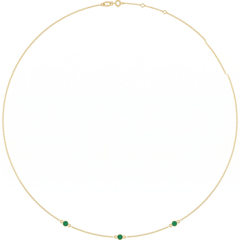 Gold chain necklace featuring three small green emerald gemstones