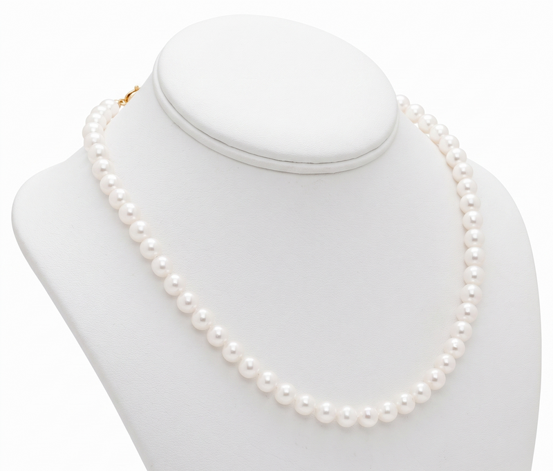 A classic strand of white freshwater pearl necklace arranged in a circle on a solid white background.